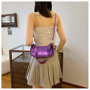 Détail des rivets argentés sur un sac bandoulière violet métallisé porté par un mannequin