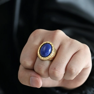 Macro shot of men's vintage gold braided ring featuring a large oval blue gemstone