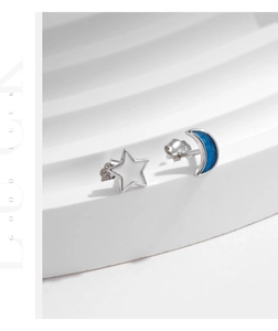 Macro view of asymmetrical S925 silver star and blue enamel moon earrings with butterfly backs