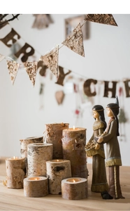 Detail of natural birch wood candle holders with rustic bark texture and tea light candles