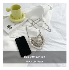 Size comparison of silver heart pearl bag next to a smartphone and a small cup