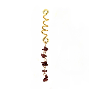 Detail of golden spiral hair ring with dark red natural stone pendant in ethnic style