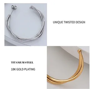 Detail of twisted double layer cross hoop earrings made of 18K gold plated titanium steel