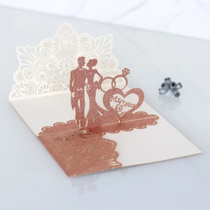 Detail of laser-cut wedding invitation featuring rose patterns and Mr & Mrs text