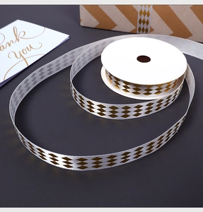 Detail of white satin ribbon with gold diamond patterns for elegant gift packaging