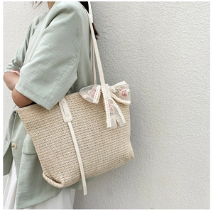 Detail of summer straw tote bag with lace bow and floral embroidery on a model
