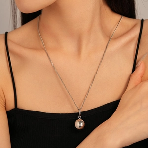 Gros plan d'un collier pendentif boule minimaliste en acier inoxydable sur un mannequin