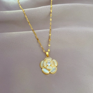 Detail of camellia flower pendant with white shell petals and gold-plated titanium steel