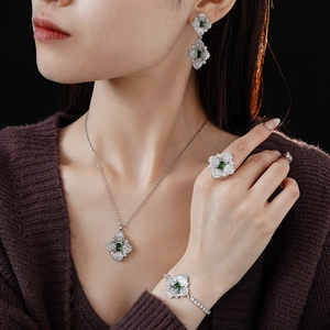 Detail view of a luxury silver jewelry set featuring green zircon flower pendants and rings