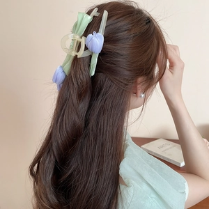 Close-up of a purple fabric tulip hair claw clip worn on long dark brown hair