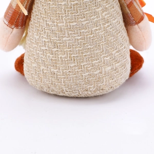 Macro detail of plush harvest gnome with beige herringbone fabric and orange felt accents