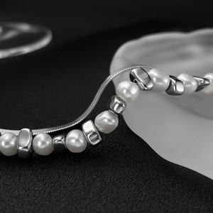 Close-up of elegant pearl and silver square bead necklace on textured black background