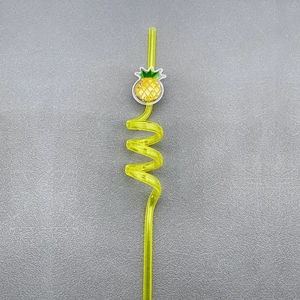 Macro detail of a yellow transparent spiral straw with a decorative pineapple charm