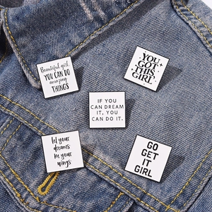 Set mit 5 quadratischen Emaille-Pins mit Motivationssprüchen auf einer Jeansjacke