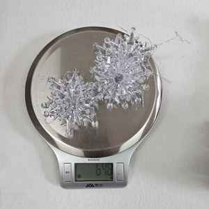 Detailed view of clear acrylic Christmas snowflake hanging on a scale weighing 67.8g
