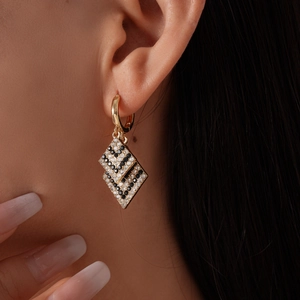 Detailed view of geometric double rhombus earrings with black and white zircon pavé