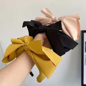 Three oversized bow headbands in yellow, black and pink made of premium textured fabric
