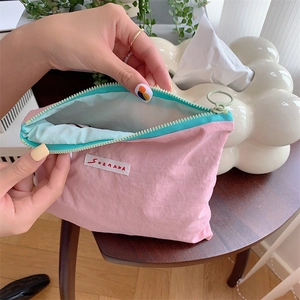 Pink macaron cosmetic bag with blue zipper showing inner fabric and brand label