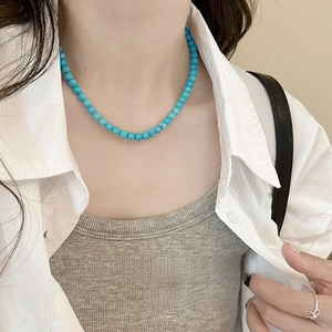 Detailed view of a turquoise beaded necklace with natural texture on a female neck