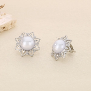 Macro shot of silver sunflower earrings featuring a white pearl and hollow metal petals