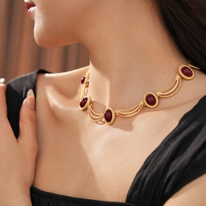 Detail of vintage gold-layered necklace with oval red gemstones worn on neck