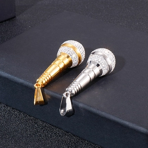 Dettaglio macro dei ciondoli a microfono oro e argento con cristalli e marchio acciaio 316L