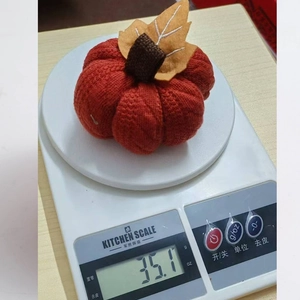Close-up of an orange knitted pumpkin weighing 35.1g on a scale for autumn decor