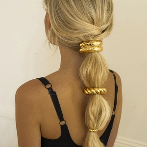 Three gold stainless steel hair ties with lava and twisted textures on a ponytail