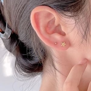 Minimalist 925 sterling silver gold flower stud earrings set on a female ear