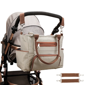 Detail of beige striped diaper bag hanging on stroller with two hook strap accessories