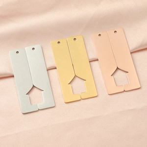 Polished hollow house pendants in silver, gold, and rose gold on pink silk background