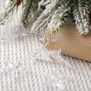 Close-up of clear acrylic reindeer and star ornaments on white knit with pine branches