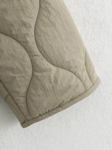 Detailed close-up of wavy quilted khaki jacket sleeve showing precision stitching and fabric