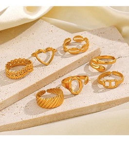 Golden 7-piece ring set featuring heart and snake motifs on natural stone surface