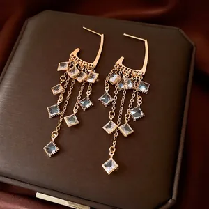 18K gold plated rhombic tassel earrings with blue gemstones on luxury silk background