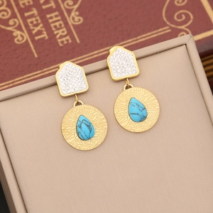 Gold-tone stud earrings with rhinestones and teardrop turquoise stones on a jewelry box
