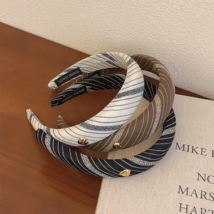 Striped sponge headbands in white, brown, and black stacked on a wooden table