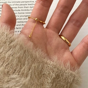 Detail shot of a layered minimalist gold ring set featuring bead chain on a female hand