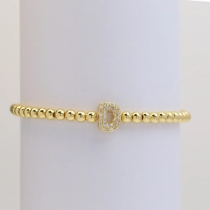 Close-up of golden beaded stretch bracelet with a sparkling cubic zirconia letter D charm