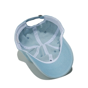 Détail intérieur de la casquette en denim bleu avec étiquette 100% coton et boucle métal