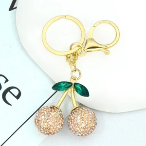 Detail of a gold cherry keychain with sparkling champagne rhinestones and green crystal leaves