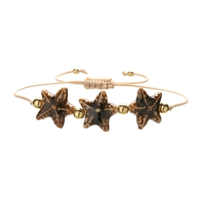 Detailed macro view of woven starfish bracelet with ceramic beads and gold spacers