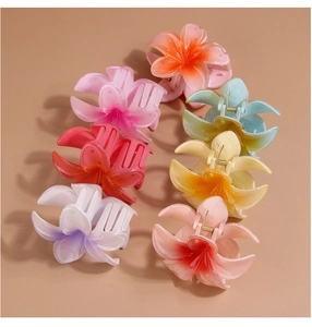Top view of seven colorful plumeria flower hair claws in a gradient of vibrant shades