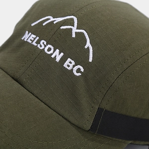 Close-up of white mountain embroidery and ripstop texture on military green cap