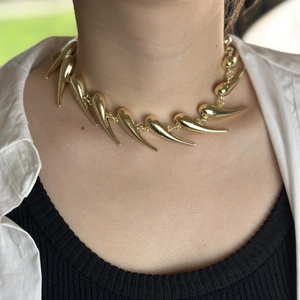 Edgy gold thorn spike necklace for women featured on a model with a stylish layered look