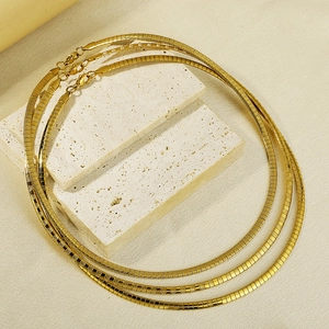 Three-piece set of golden titanium steel flat snake chains on a white stone background