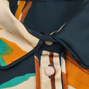 Detail of satin shirt collar featuring abstract patterns and gold-rimmed pearl buttons