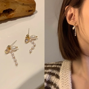 Detailed view of gold heart pearl drop earrings with crystal studs on an Asian model