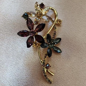 Close-up of vintage flower brooch with purple crystals and gold alloy base on pink satin