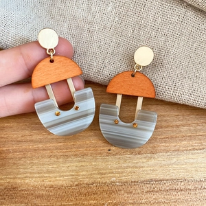 Macro shot of U-shaped resin drop earrings with wood grain texture and gold accents